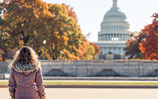 a young woman stands facing the U.S. Capitol in Washington D.C.