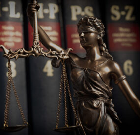 a small statute of justice, in front of a row of law books